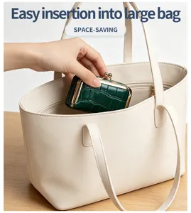 Nahaufnahme einer grünen Ledertasche, die in eine große cremefarbene Handtasche gesteckt wird