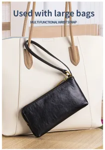 Close-up of a black leather wristlet wallet attached to a large white tote handbag