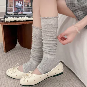 Detail of grey thin stirrup leg warmers featuring wood ear ruffled edges and slouchy fit