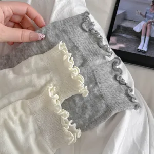 Close-up of sweet ruffle-edged leg warmers in thin breathable white and gray fabric