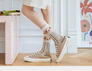 Close-up of breathable floral glass silk socks paired with khaki canvas mule sneakers.
