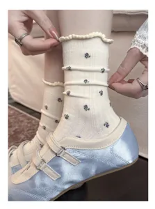 Close-up of cream floral crew socks with ruffled cuffs and dainty purple patterns