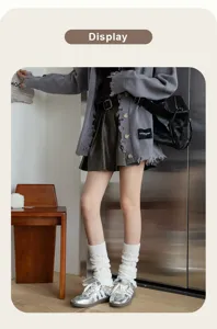 Detail shot of cozy white cable knit leg warmers worn with silver shoes, Y2K aesthetic style.