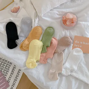 Selection of vibrant dopamine colored ribbed invisible boat socks on a white cozy bed