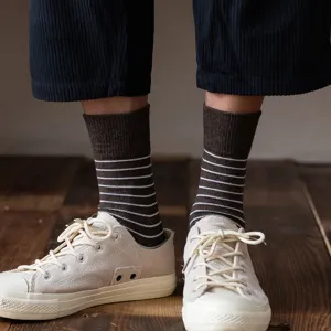 Vintage brown and white striped crew socks for men styled with beige canvas sneakers.