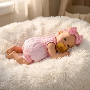 Realistic 12-inch solid silicone baby doll in pink checkered romper on a white rug