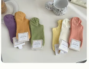 Detailed view of colorful ribbed cotton boat socks with brand tags on white surface.