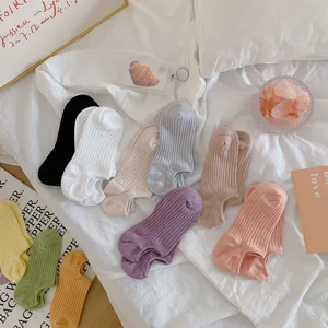 Detailed view of colorful ribbed no-show socks in vibrant dopamine shades on white linen