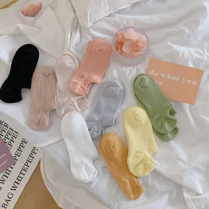 Detailed view of colorful ribbed invisible socks on soft white bedding lifestyle background