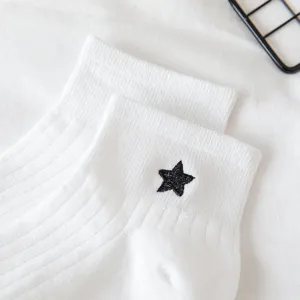 Close-up detail of white cotton short socks featuring stylish black star embroidery on the cuff.