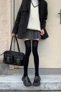 Calcetines altos negros térmicos para invierno combinados con falda plisada y mocasines.