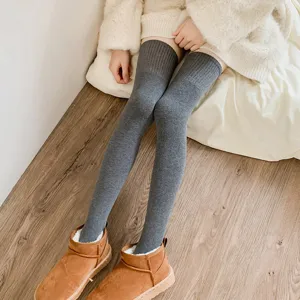 Calcetines térmicos grises por encima de la rodilla para mujer con botas de invierno elegantes