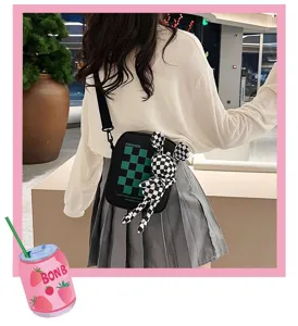Primer plano de un bolso bandolera de cuadros negro y verde estilo japonés con muñeco conejo