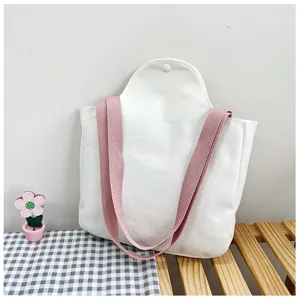 Gedetailleerd zijdelings aanzicht van witte canvas tas met roze riemen op een houten bank