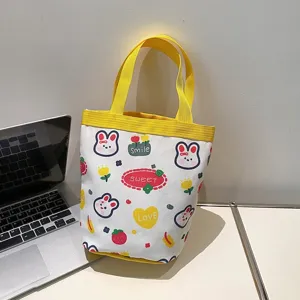 Cute cartoon canvas tote bag with bunny prints and yellow straps next to a laptop