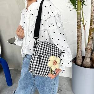Detalle de mini bolso bandolera de cuadros blanco y negro con adorno de flor decorativa.