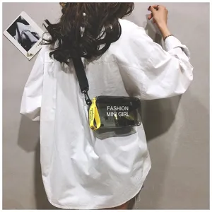 Detailweergave van een stijlvolle transparante zwarte jelly crossbodytas op een wit shirt.