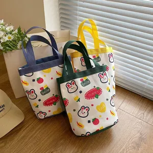 A detailed view showing three cute cartoon bunny canvas tote bags in blue, green, and yellow.