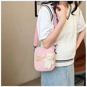 Vista detallada de un lindo bolso bandolera de nailon rosa con un oso de peluche blanco en modelo