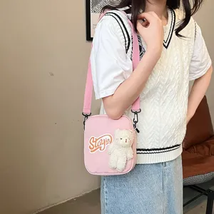 Primer plano de bolso bandolera de nailon rosa con un lindo peluche de oso blanco