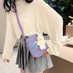 Chica que lleva un bolso bandolera japonés morado con un lindo peluche de conejo blanco suave