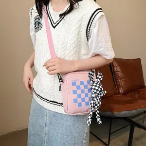 Detalle del bolso bandolera rosa a cuadros con un adorable peluche de conejo.