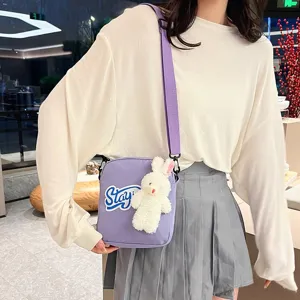 Vista detallada del bolso bandolera morado con un lindo colgante de conejo de peluche