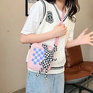 Bolso de hombro rosa con patrón de cuadros y detalle de accesorio de muñeco conejo