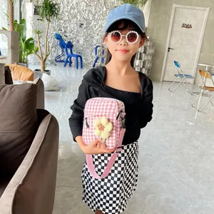 Primer plano de una niña modelo con un bolso mini de cuadros rosas y un girasol.