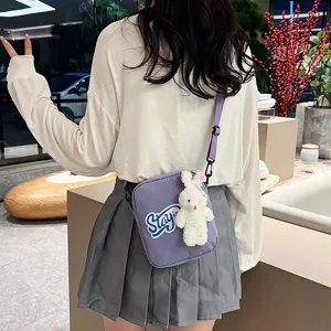 Vista detallada del bolso bandolera morado con un peluche de conejo blanco en un modelo