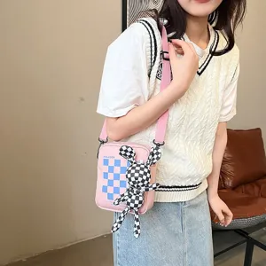 Vista detallada del bolso bandolera rosa con estampado de cuadros y muñeco conejo