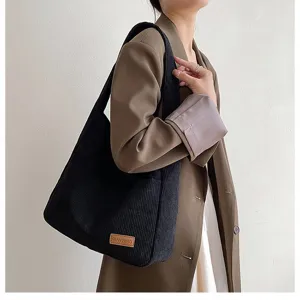 Large black corduroy tote bag for women worn by a model in a brown blazer