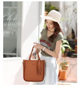 Asiatisches Model hält stilvolle braune Handtasche mit Quasten aus Kieselleder