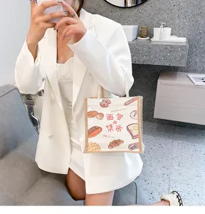 Detailaufnahme einer stylischen Canvas-Tasche mit süßen Brot-Doodles, gehalten von Modell.