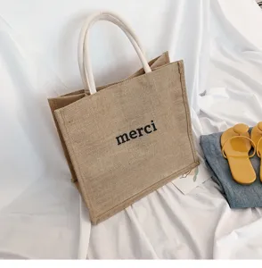Detailed view of natural jute tote bag featuring merci print and soft cotton handles