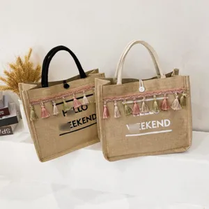 Detailed view of jute tote bags with colorful tassels and Hello Weekend print