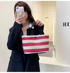 Sac à main tendance en paille tressée à rayures rouges et blanches tenu par un mannequin