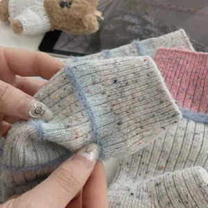 Close-up view of knitted wool socks with colorful flecks and fuzzy striped texture details.
