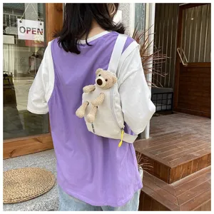 Back view of a cute white canvas chest bag featuring a plush teddy bear attachment