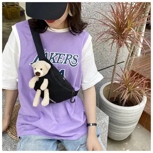 Detailed view of black canvas fanny pack with a plush teddy bear accessory on a model