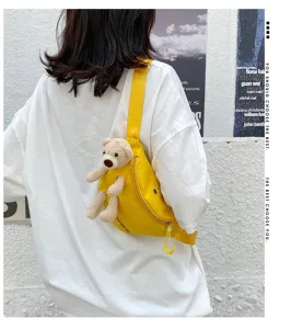 Close-up of a yellow canvas chest bag with a cute plush bear decoration worn by a model