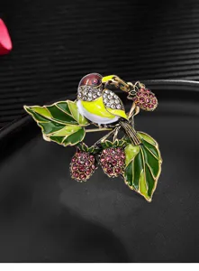 Detailed view of vintage enamel magpie brooch with colorful rhinestones and berries.