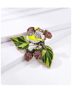 Close-up of vintage magpie brooch with pink rhinestones and green enamel leaves