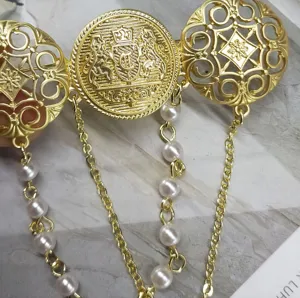 Dettaglio ravvicinato di una spilla araldica vintage in oro con catenine di perle