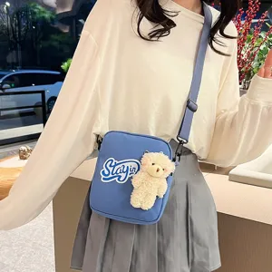 Bolso bandolera de nylon azul con un peluche de osito y un parche de letras moda