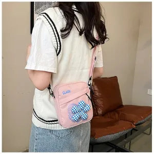 Detalle de un bolso bandolera rosa de estilo académico con un adorno de flor