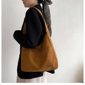 Detail view of a large capacity mustard corduroy tote bag styled on a model.