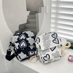 Primer plano de bolsos bandolera de nailon con estampados de osos y corazones en blanco y negro