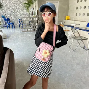 Niña con mini bolso bandolera moderno de cuadros rosas con flor en un ambiente de café chic.