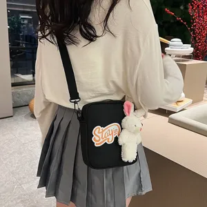 Detalle de bolso bandolera negro de estilo japonés con amuleto de conejo y parche